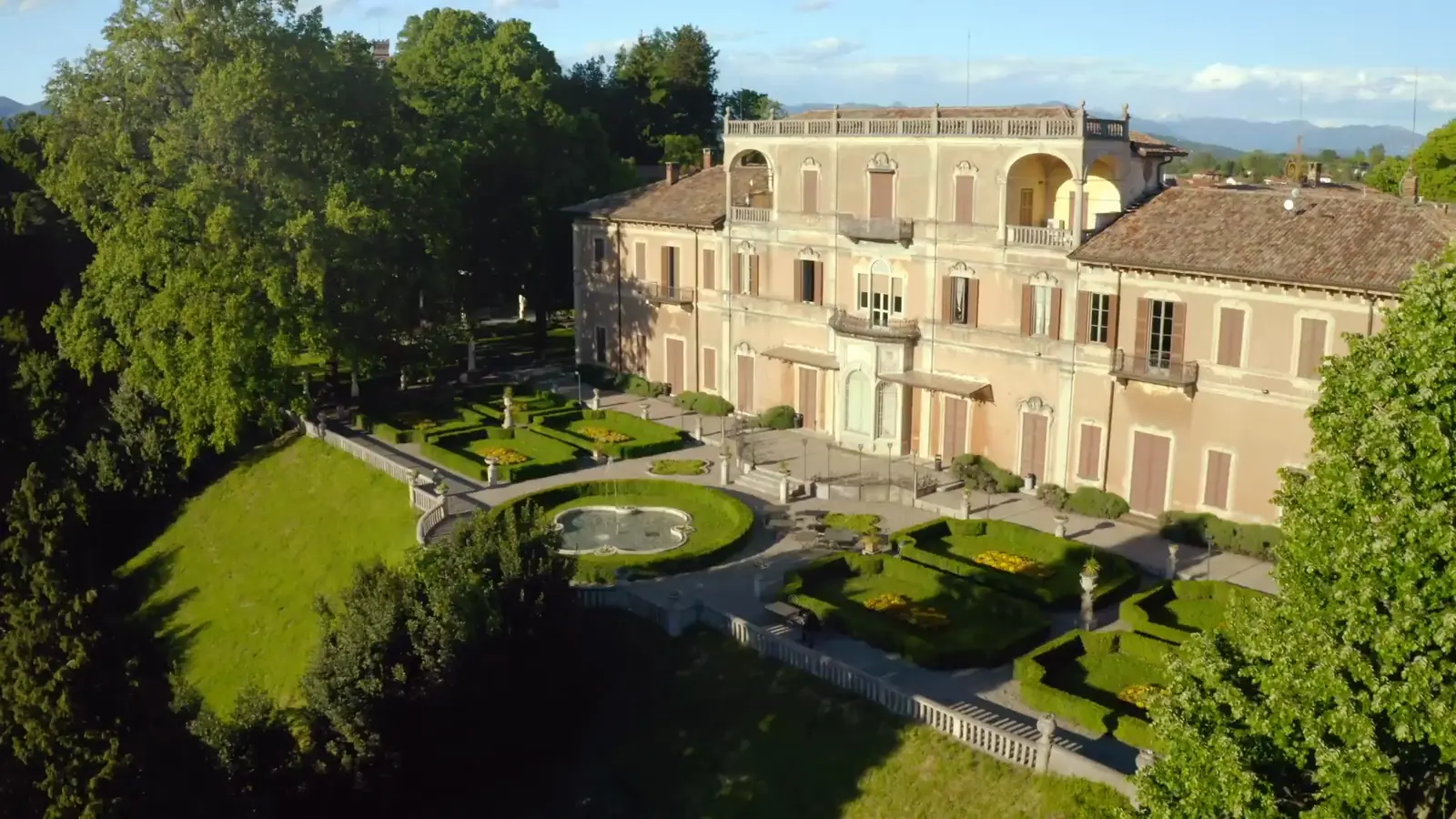 Villa Cagnola dall'alto: la facciata al sole del pomeriggio e il giardino all'italiana con la fontana