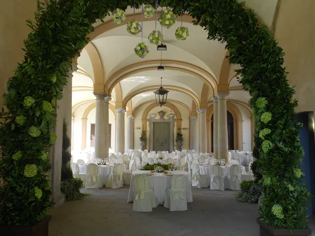 Il porticato della villa apparecchiato per una festa, sotto un arco di verde