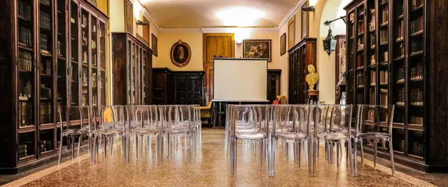 La sala Biblioteca, con le librerie antiche alle pareti e le sedie trasparenti pronte per una riunione