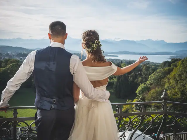 Due sposi, di spalle, sulla balaustra della villa guardano il lago di Varese e le Alpi